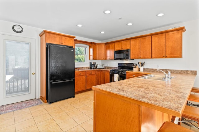 kitchen featuring sink, a kitchen breakfast bar, kitchen peninsula, light tile patterned floors, and black appliances