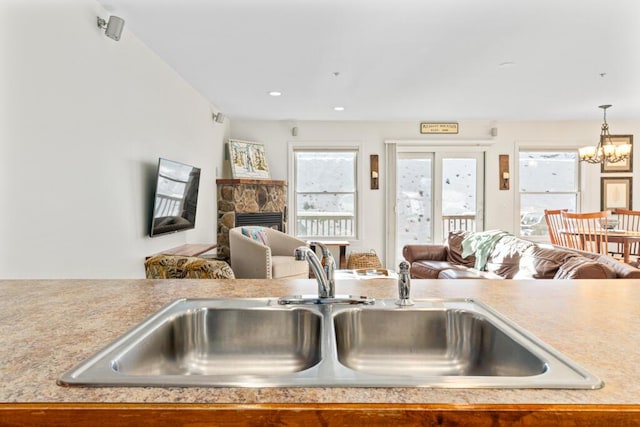 kitchen with pendant lighting, sink, a fireplace, and an inviting chandelier