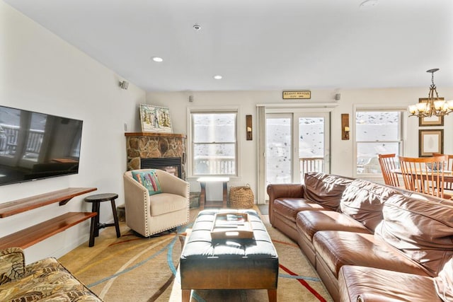 carpeted living room with a notable chandelier and a stone fireplace