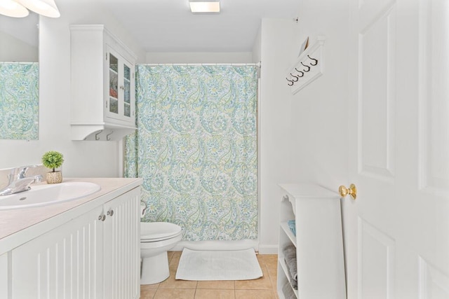 bathroom with toilet, vanity, and tile patterned floors