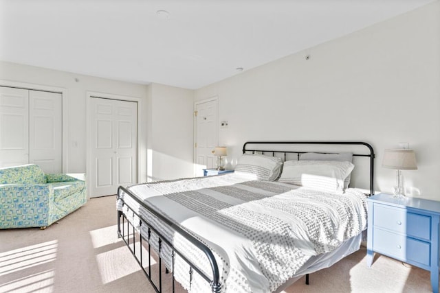 bedroom featuring two closets and light colored carpet