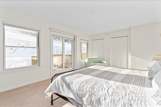 bedroom featuring light colored carpet and two closets