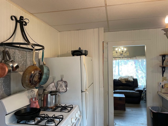 kitchen with an inviting chandelier, white range, a paneled ceiling, wooden walls, and hardwood / wood-style flooring