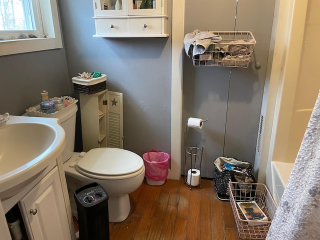 bathroom featuring hardwood / wood-style floors, vanity, a tub to relax in, and toilet