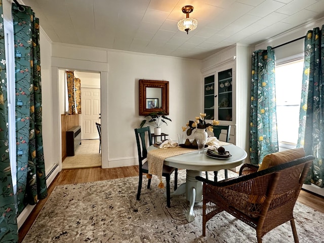 dining room with ornamental molding, a baseboard heating unit, and light hardwood / wood-style floors