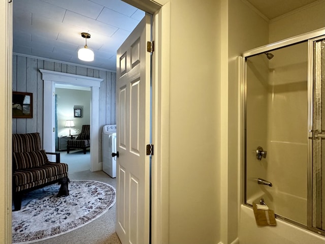 bathroom featuring crown molding, enclosed tub / shower combo, wooden walls, and washer / dryer