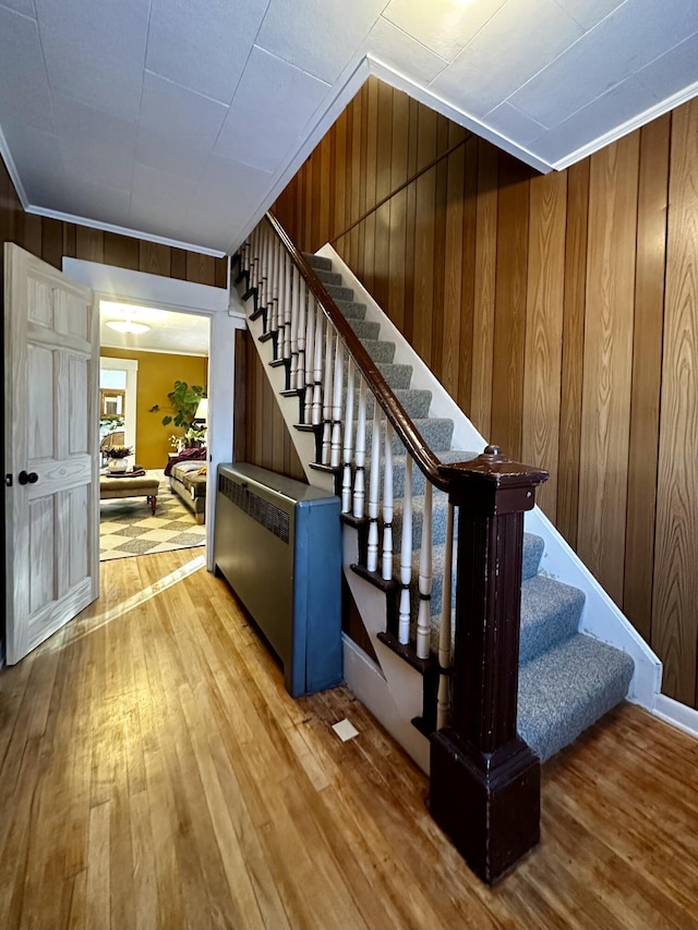 stairway featuring hardwood / wood-style flooring and wood walls