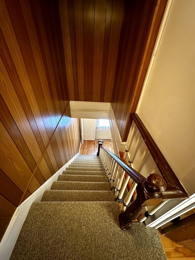 staircase featuring wooden walls