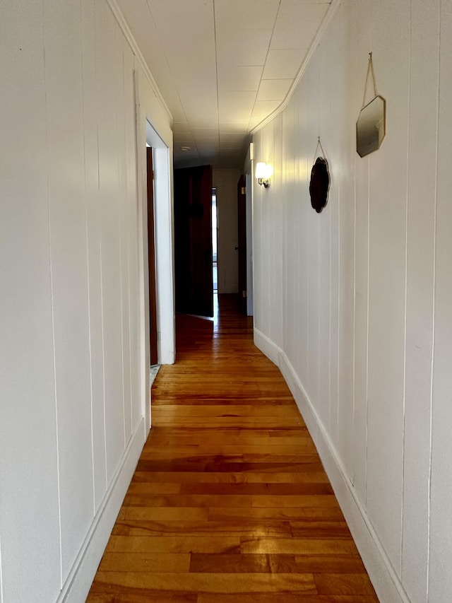 hallway with wood-type flooring and crown molding