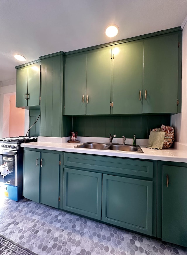 kitchen with stainless steel gas range oven, sink, and green cabinets