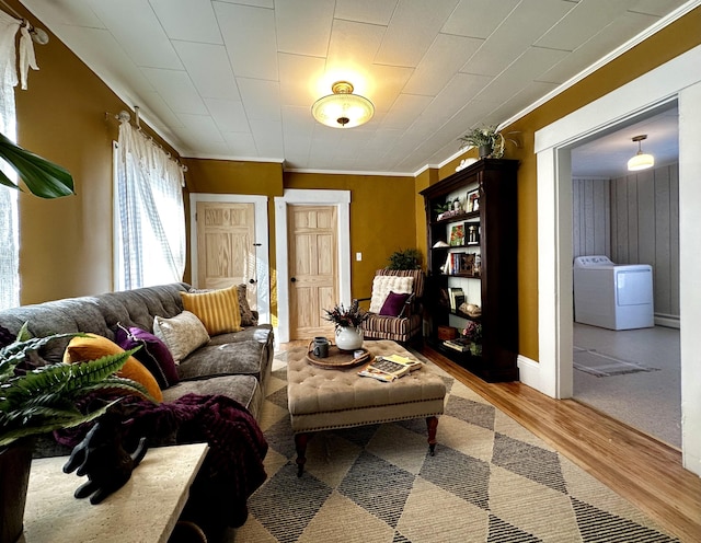 living room featuring crown molding, independent washer and dryer, and hardwood / wood-style floors