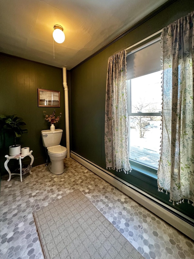 bathroom with wooden walls, baseboard heating, and toilet