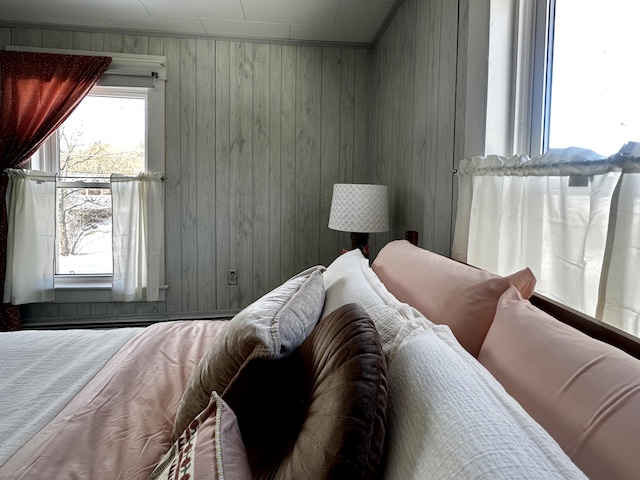 bedroom with multiple windows and wooden walls