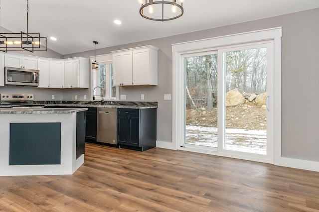 kitchen with an inviting chandelier, stainless steel appliances, pendant lighting, white cabinets, and stone countertops