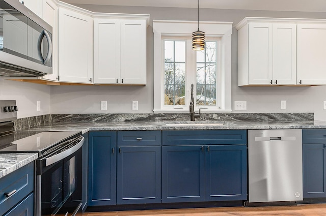 kitchen featuring sink, blue cabinets, white cabinetry, hanging light fixtures, and appliances with stainless steel finishes