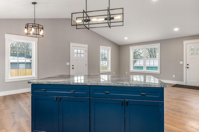 kitchen featuring light hardwood / wood-style flooring, blue cabinetry, lofted ceiling, and plenty of natural light