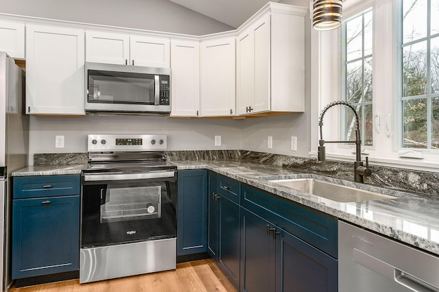 kitchen featuring stainless steel appliances, white cabinets, blue cabinetry, and sink