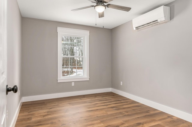 unfurnished room with ceiling fan, a wall unit AC, and wood-type flooring