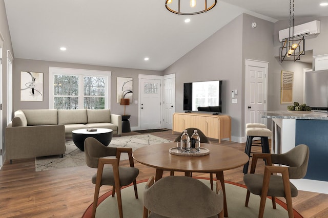 dining area with a wall mounted AC, light wood-type flooring, and high vaulted ceiling