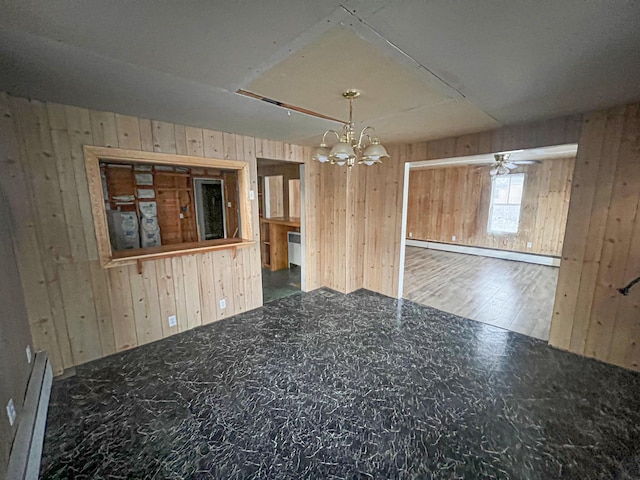 unfurnished room with ceiling fan with notable chandelier, wooden walls, baseboard heating, and dark wood-type flooring