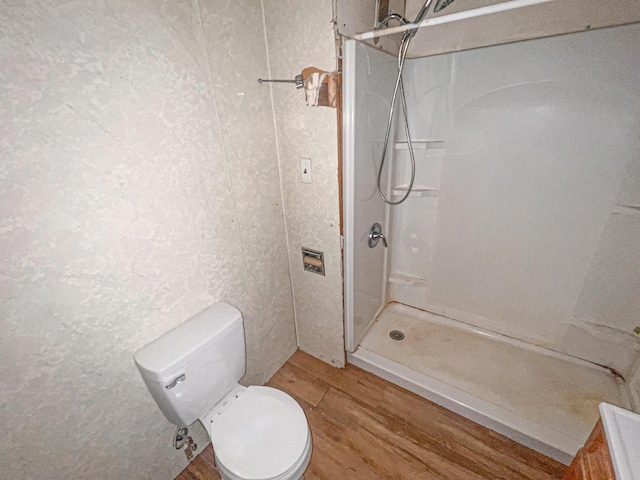 bathroom with a shower, toilet, and hardwood / wood-style flooring