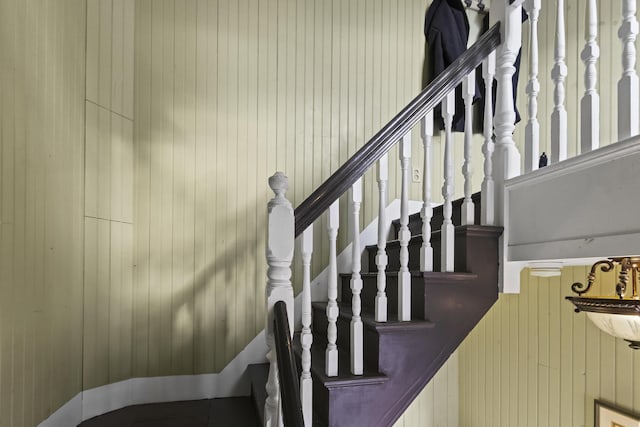 stairway featuring wooden walls