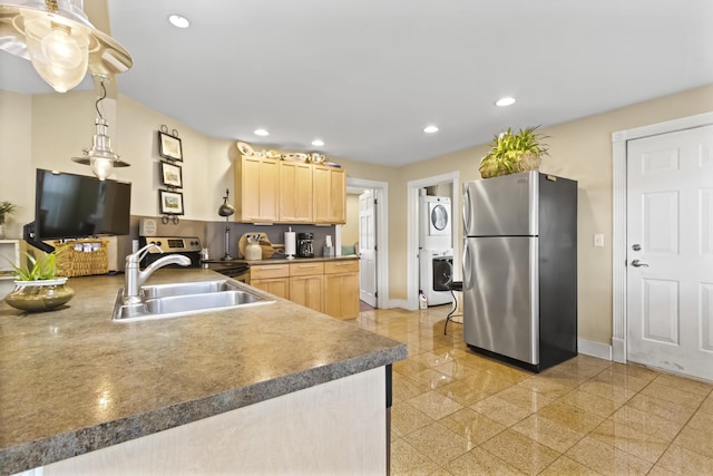 kitchen featuring light brown cabinets, sink, appliances with stainless steel finishes, decorative light fixtures, and stacked washer / dryer