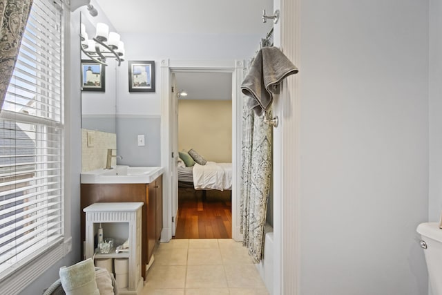 full bathroom with shower / bath combination with curtain, vanity, tile patterned flooring, a chandelier, and toilet