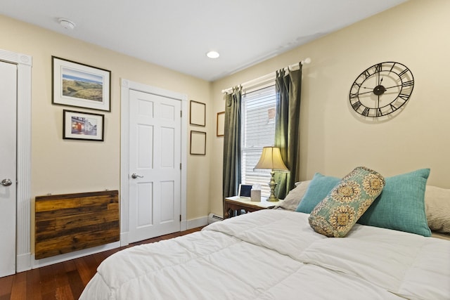 bedroom with dark hardwood / wood-style flooring and a baseboard heating unit