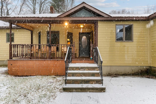 snow covered property entrance featuring a porch