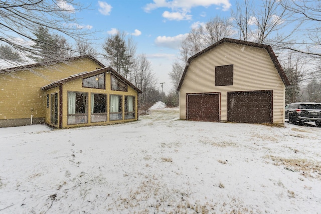 view of snowy exterior with an outbuilding and a garage