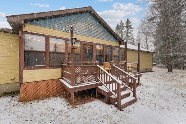 snow covered house featuring a sunroom