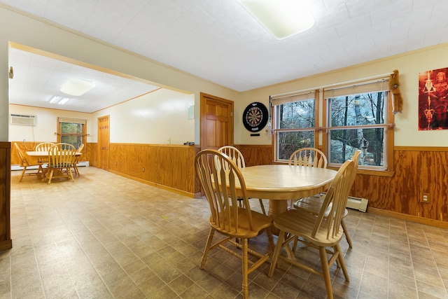 dining room with ornamental molding, wooden walls, and a baseboard radiator