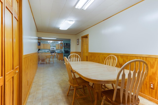 dining room with ornamental molding and wooden walls