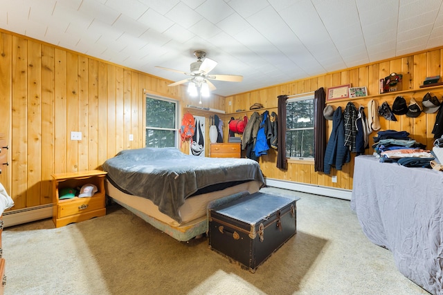 carpeted bedroom featuring baseboard heating, wood walls, and ceiling fan