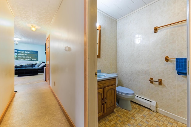 bathroom with vanity, toilet, baseboard heating, and tile walls