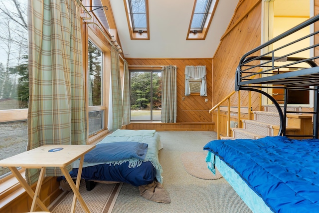 bedroom with carpet, wood walls, high vaulted ceiling, and a skylight