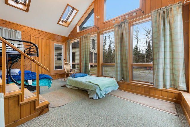 carpeted bedroom featuring a skylight, high vaulted ceiling, and wood walls