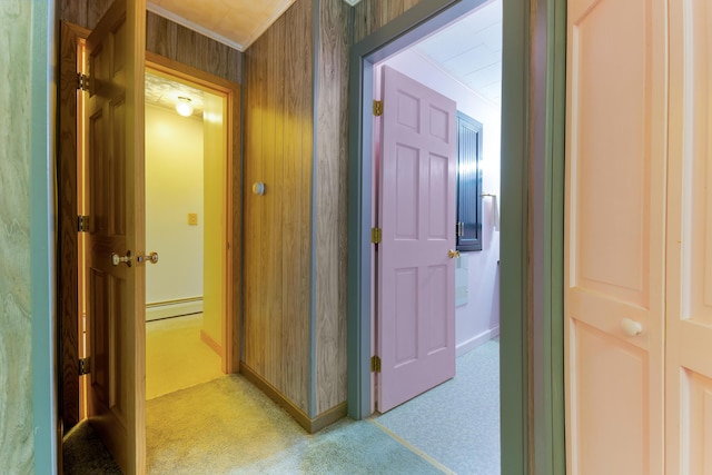 corridor with light colored carpet, baseboard heating, and wooden walls