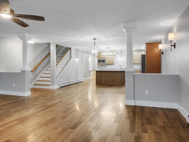 unfurnished living room featuring a chandelier, baseboard heating, and light hardwood / wood-style flooring