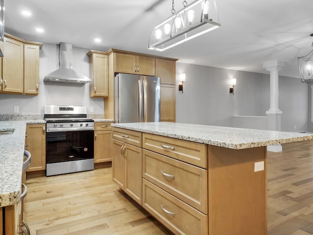 kitchen featuring a center island, light hardwood / wood-style flooring, wall chimney exhaust hood, ornate columns, and appliances with stainless steel finishes