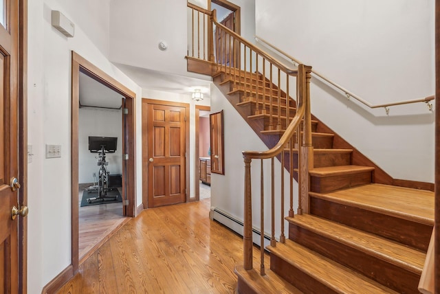 stairs with baseboard heating and hardwood / wood-style floors