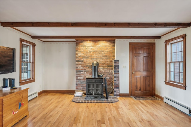 unfurnished living room featuring plenty of natural light, a wood stove, and a baseboard heating unit