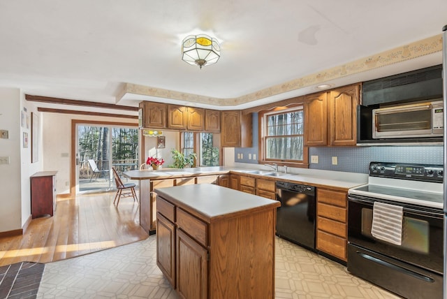 kitchen with a center island, black appliances, sink, decorative backsplash, and kitchen peninsula