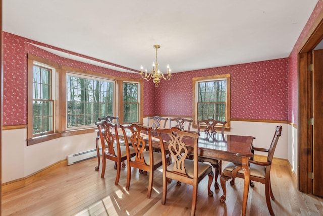 dining area with a baseboard radiator, light hardwood / wood-style flooring, a wealth of natural light, and a chandelier