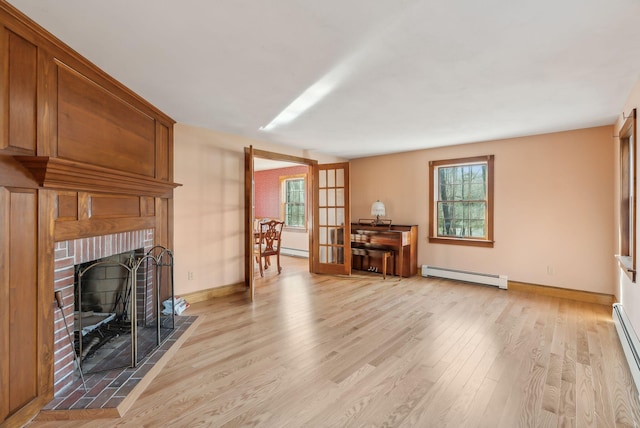 living room featuring light hardwood / wood-style flooring, a brick fireplace, plenty of natural light, and a baseboard heating unit