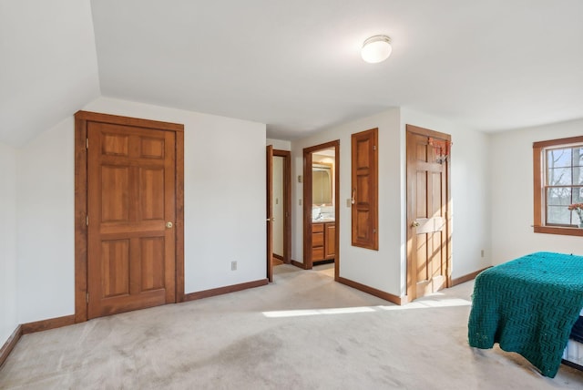 unfurnished bedroom with light colored carpet, lofted ceiling, and connected bathroom