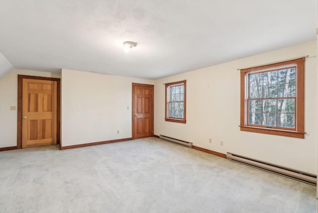 carpeted spare room featuring baseboard heating and vaulted ceiling