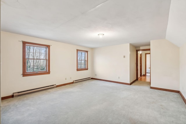 unfurnished room featuring light carpet, vaulted ceiling, and a baseboard heating unit