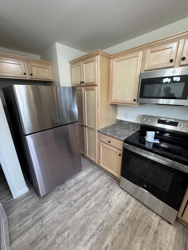 kitchen featuring light brown cabinets, stainless steel appliances, and light wood-type flooring